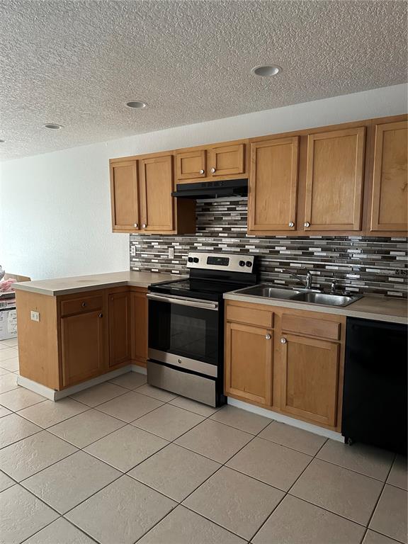 A kitchen features light wood cabinets, stainless steel appliances, a tiled backsplash, and beige floor tiles — 752 E BROOME STREET UNIT 756, CLERMONT, FL