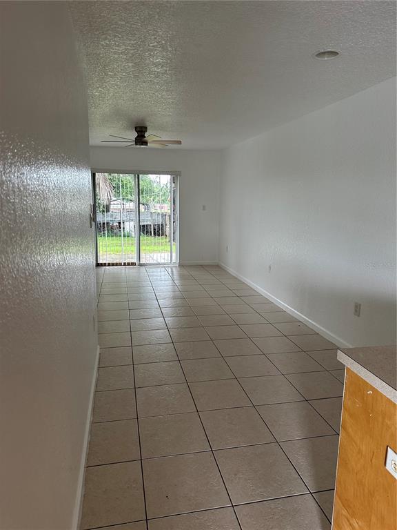 A room with light-colored tile flooring, white walls, a ceiling fan, and sliding glass doors — 752 E BROOME STREET UNIT 756, CLERMONT, FL