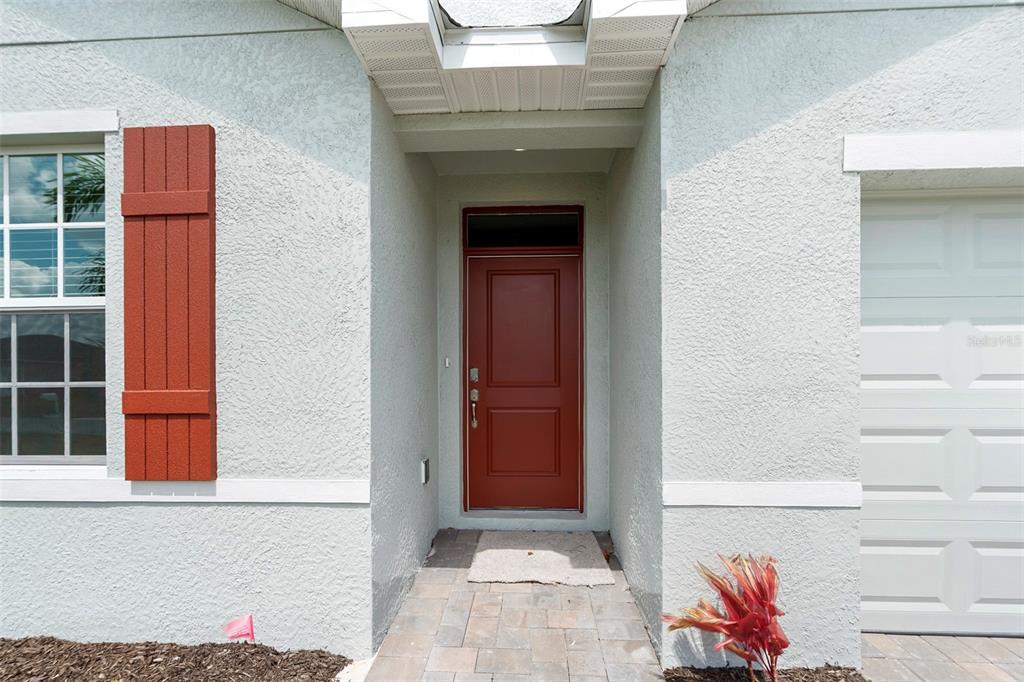 The exterior view shows a red front door, a window with red shutters, and stucco — 25222 CADIZ DRIVE, PUNTA GORDA, FL