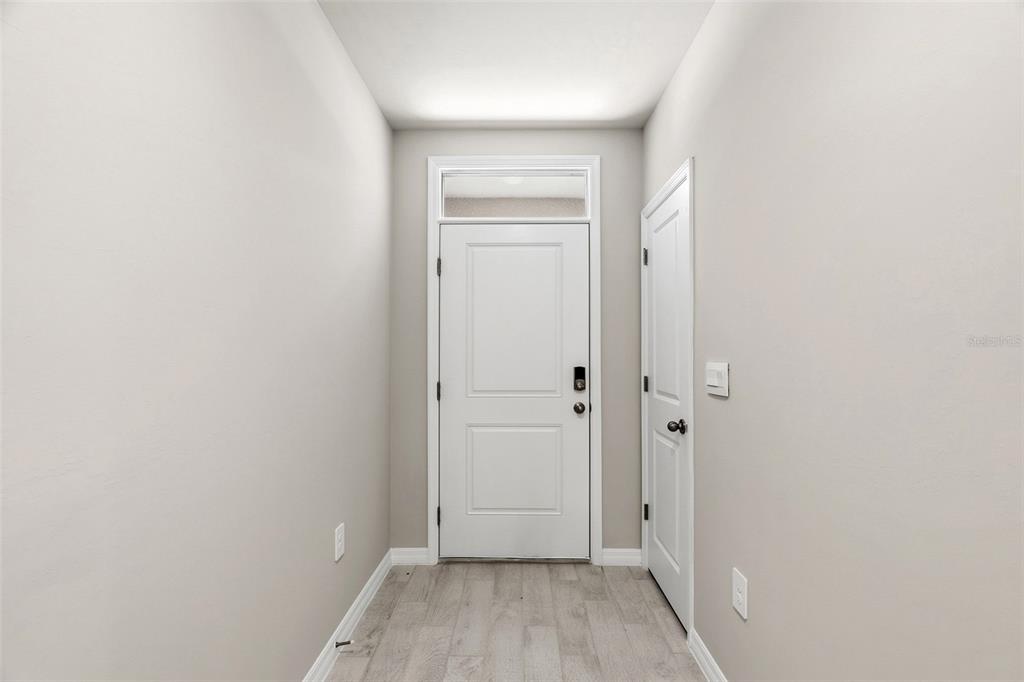 A bright entryway features a white front door, a side door, and light wood-look flooring — 25222 CADIZ DRIVE, PUNTA GORDA, FL