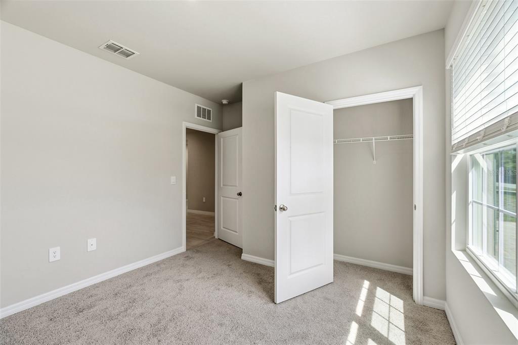 A bedroom with gray carpet, light-colored walls, a closet, and a window with blinds — 25222 CADIZ DRIVE, PUNTA GORDA, FL