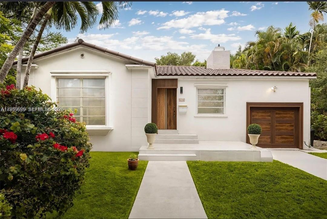 A white single-story house with a tile roof, wood-accented door, and a front lawn — 528 Sevilla Ave, Coral Gables FL 33134, CORAL GABLES, FL
