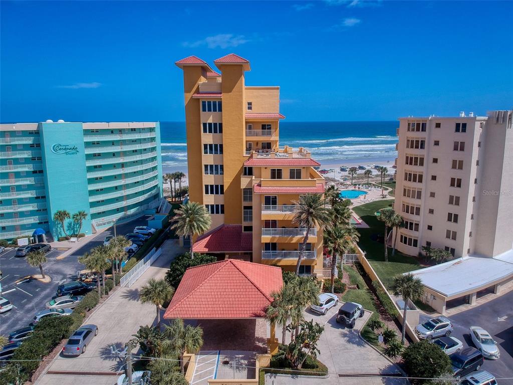 An aerial view of a multi-story yellow apartment building with a red tile roof — 701 N ATLANTIC AVENUE UNIT 401, NEW SMYRNA BEACH, FL