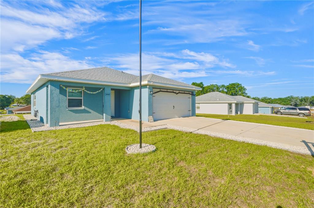 A light blue single-story house with a two-car garage and a front yard — 4447 E TAPER STREET, INVERNESS, FL