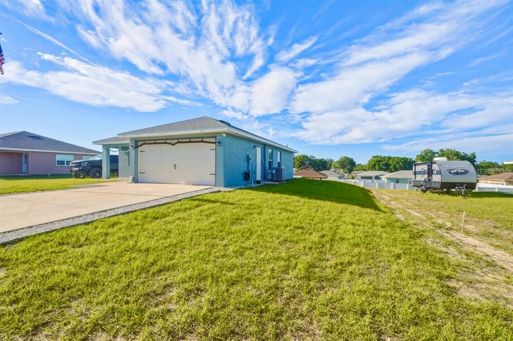 A blue single-story house with a two-car garage and a camper parked on the lawn — 4447 E TAPER STREET, INVERNESS, FL