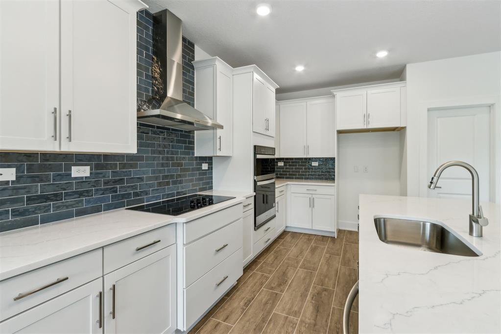 A modern kitchen features white cabinets, a dark blue subway tile backsplash, and a kitchen island — 96100 Pirates Bluff Road, FL 32097, FL