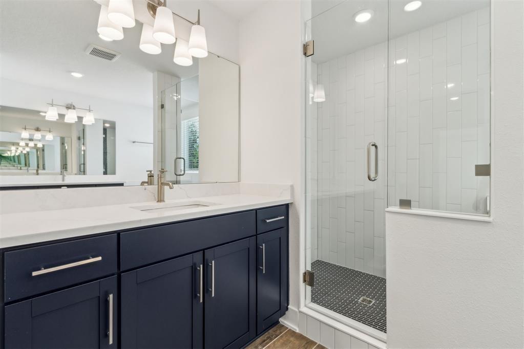 A bathroom features a dark blue vanity, white countertop, and a glass-enclosed walk-in shower — 96100 Pirates Bluff Road, FL 32097, FL