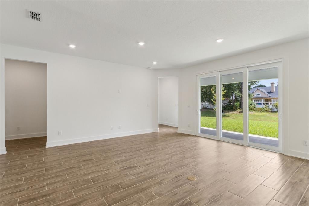 An empty room with wood-look tile flooring, recessed lighting, and sliding glass doors to a yard — 96100 Pirates Bluff Road, FL 32097, FL