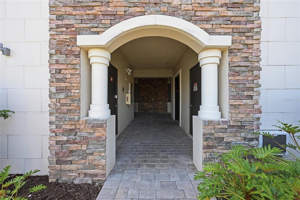 A stone-accented arched entryway leads to a paved walkway between two dark entry doors — 16904 VARDON TERRACE UNIT 205, LAKEWOOD RANCH, FL