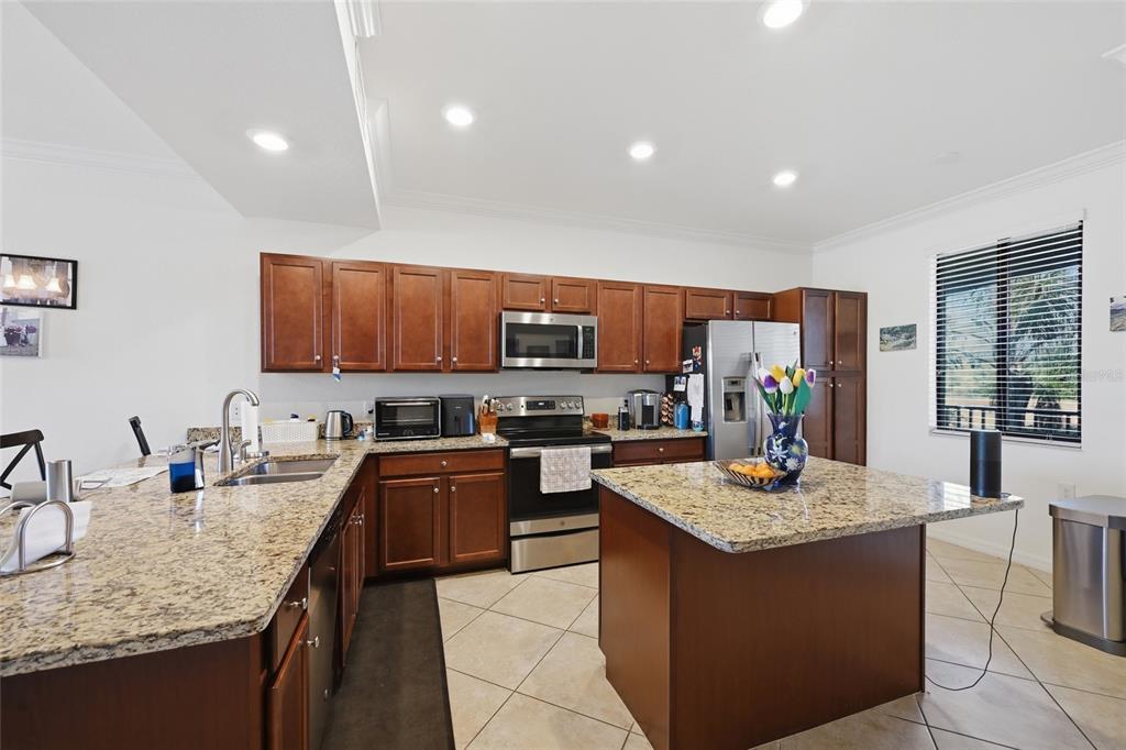 A kitchen features wood cabinets, granite countertops, stainless steel appliances, and a central island — 16904 VARDON TERRACE UNIT 205, LAKEWOOD RANCH, FL