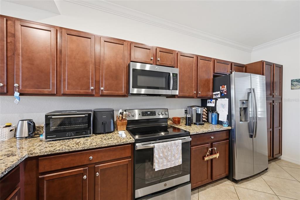 A kitchen features dark wood cabinets, granite countertops, and stainless steel appliances — 16904 VARDON TERRACE UNIT 205, LAKEWOOD RANCH, FL
