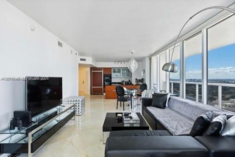 A modern living room features a large television, a sectional sofa, and floor-to-ceiling windows — 1830 S Ocean Dr # 3308, Hallandale Beach FL 33009, HALLANDALE BEACH, FL