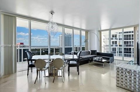 A modern dining and living area with floor-to-ceiling windows, a chandelier, and marble flooring — 1830 S Ocean Dr # 3308, Hallandale Beach FL 33009, HALLANDALE BEACH, FL
