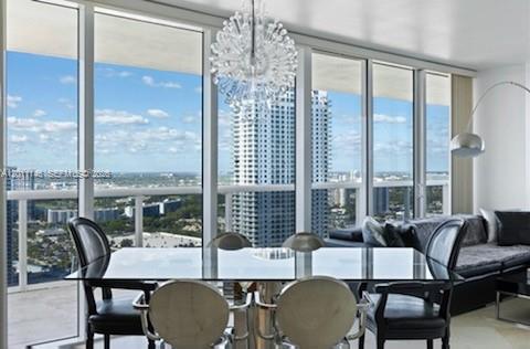 A dining area with a glass table, four chairs, and a chandelier overlooking a city view — 1830 S Ocean Dr # 3308, Hallandale Beach FL 33009, HALLANDALE BEACH, FL