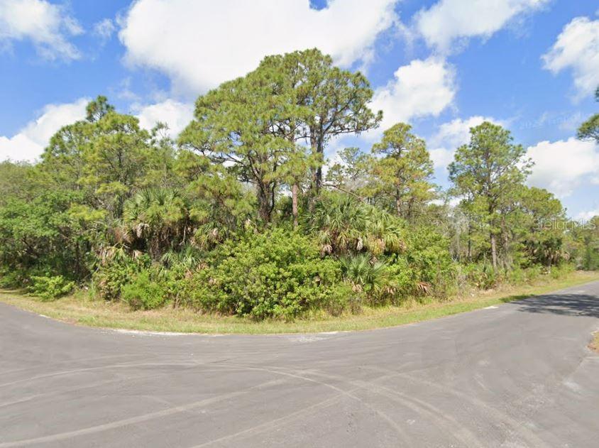 A vacant, wooded corner lot sits at the intersection of two paved residential streets — 1376 CALICO LANE, PORT CHARLOTTE, FL