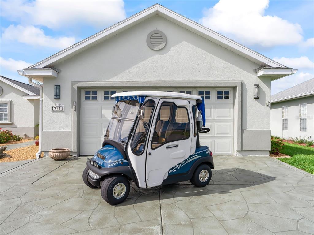 A blue and white golf cart is parked on a stamped concrete driveway in front of a house — 12211 SE 175TH LOOP, SUMMERFIELD, FL