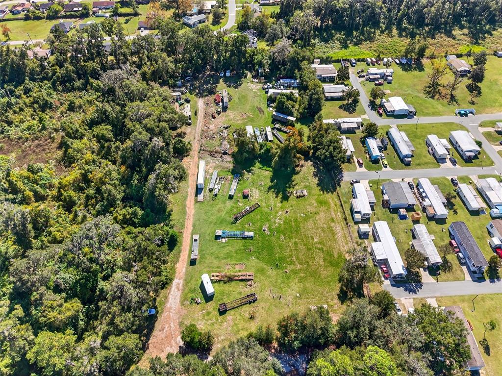 An aerial view shows a large grassy lot with scattered trailers adjacent to a neighborhood — 10389 SE 50TH AVENUE, BELLEVIEW, FL