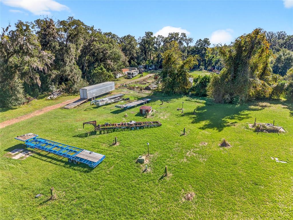 An aerial view of a grassy lot containing several flatbed trailers and a storage container — 10389 SE 50TH AVENUE, BELLEVIEW, FL
