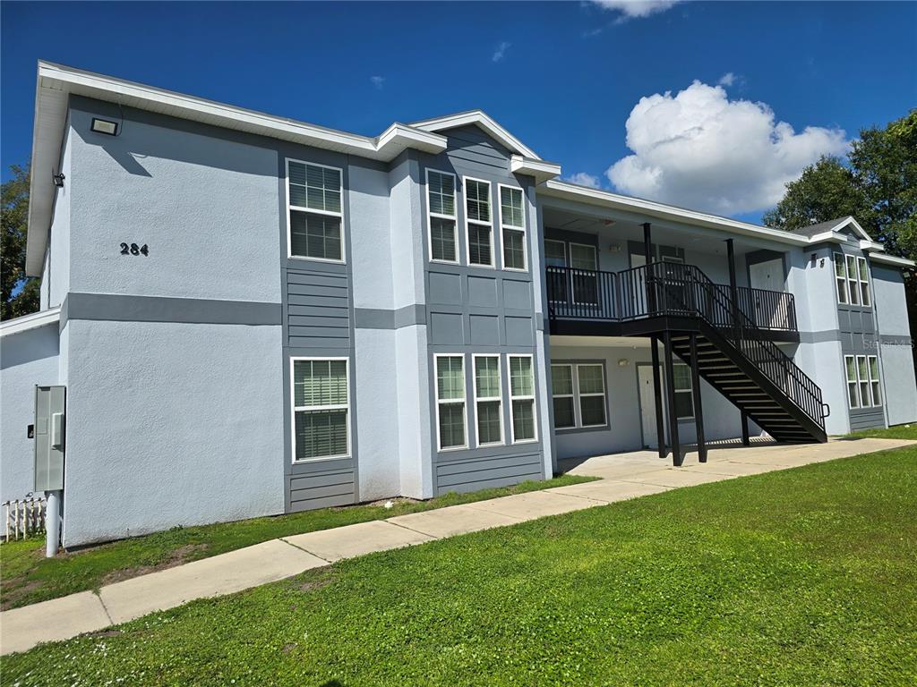 A two-story apartment building with light blue stucco siding and an exterior metal staircase — 284 GARDNER LANE UNIT F, KISSIMMEE, FL