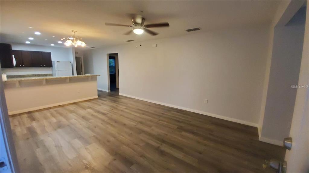An open-concept living area features wood-look flooring, a ceiling fan, and a kitchen breakfast bar — 284 GARDNER LANE UNIT F, KISSIMMEE, FL