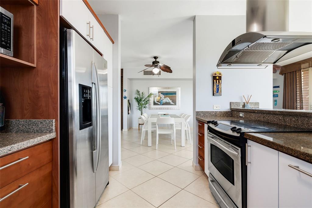 A kitchen with stainless steel appliances and granite countertops leads into a dining area — 75 OCEAN DRIVE UNIT 336, HUMACAO, PR