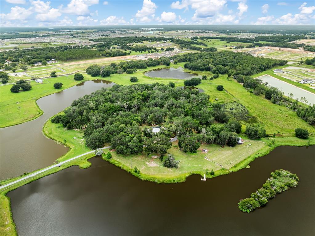 An aerial view shows a house nestled in a wooded area surrounded by lakes — 33415 KIEFER ROAD, WESLEY CHAPEL, FL