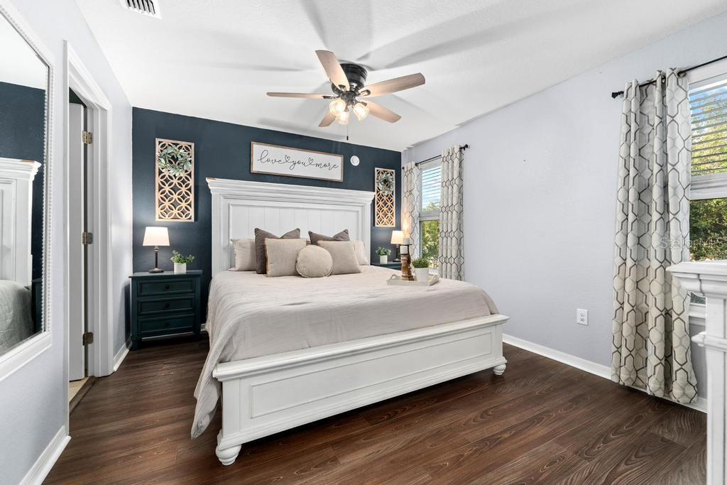 A bedroom features a white bed frame, dark blue accent wall, and wood-look flooring — 10427 RIVERCREST DRIVE, RIVERVIEW, FL