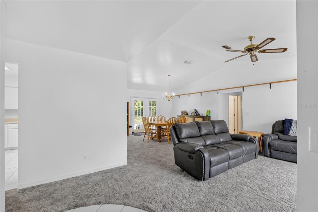 A living room with gray carpet and a dining area with a wooden table set — 9590 SE 190TH COURT, OCKLAWAHA, FL