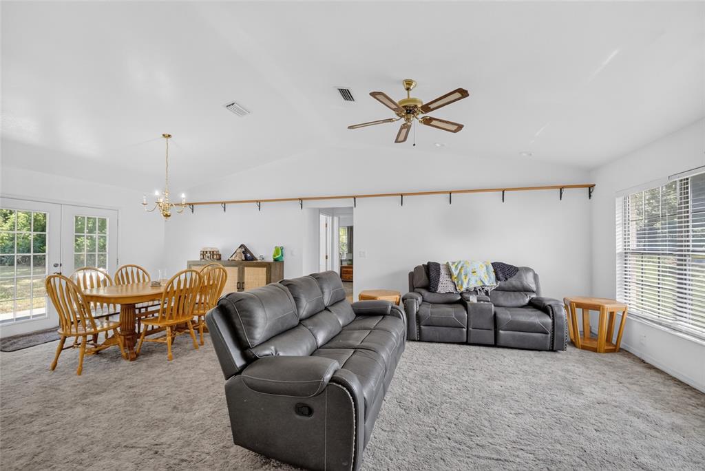 A living and dining area with gray carpet, a vaulted ceiling, and gray leather furniture — 9590 SE 190TH COURT, OCKLAWAHA, FL