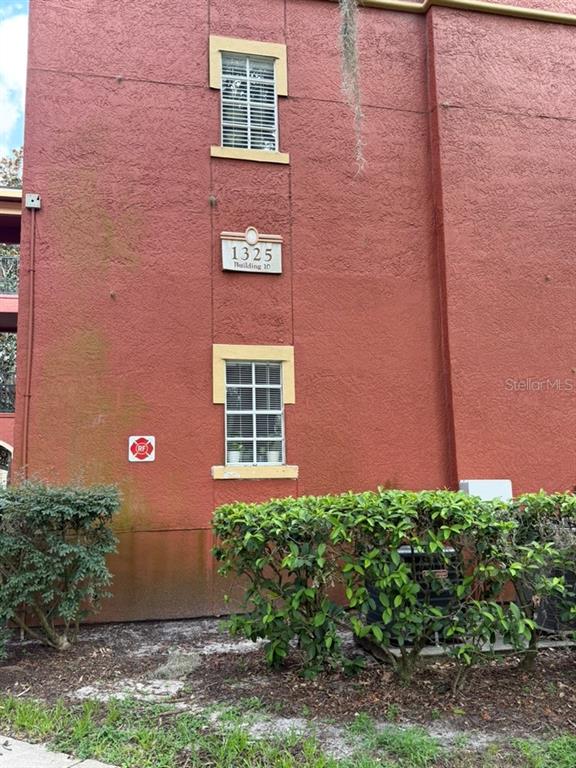 The exterior of a red stucco building features two windows and a building number sign — 1325 ROTONDA POINT UNIT 225, LAKE MARY, FL