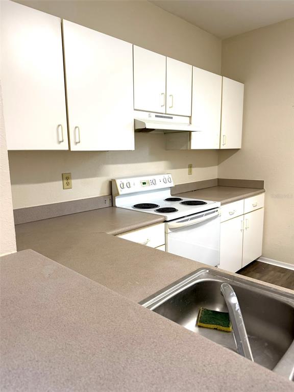 A kitchen features white cabinets, a white electric stove, and a stainless steel sink — 1325 ROTONDA POINT UNIT 225, LAKE MARY, FL