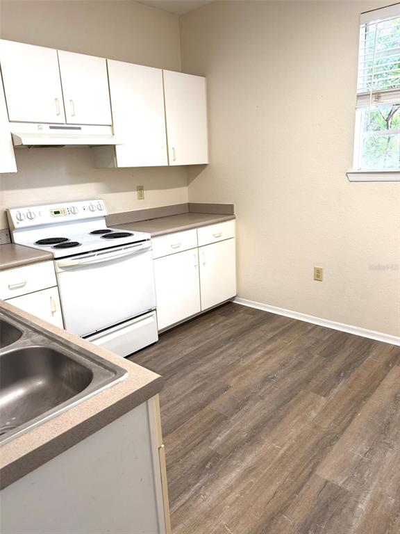 A kitchen features white cabinets, a white stove, and wood-look flooring — 1325 ROTONDA POINT UNIT 225, LAKE MARY, FL