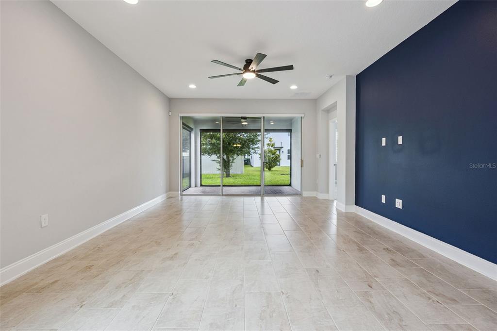 A living room features light tile flooring, a dark blue accent wall, and sliding glass doors — 12248 ENCORE AT OVATION WAY, WINTER GARDEN, FL