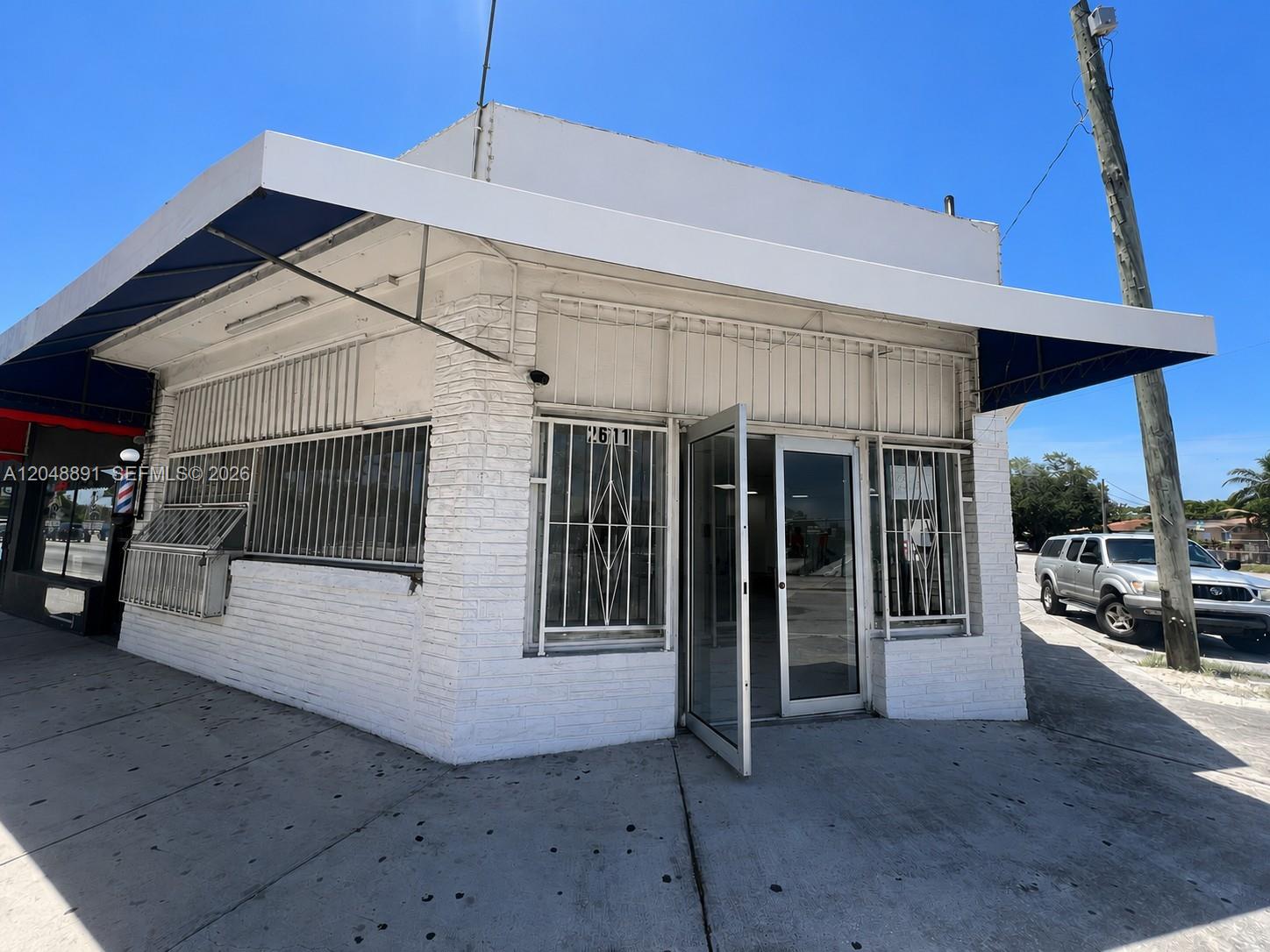 A white brick commercial building with a blue awning and security bars on the windows — 2601 W Flagler St, Miami FL 33135, MIAMI, FL