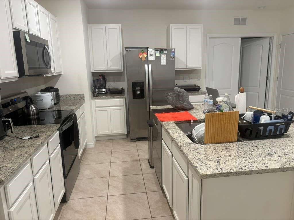 A kitchen featuring white cabinets, granite countertops, stainless steel appliances, and a central island — 2343 AQUILINE NEST STREET, EAGLE LAKE, FL
