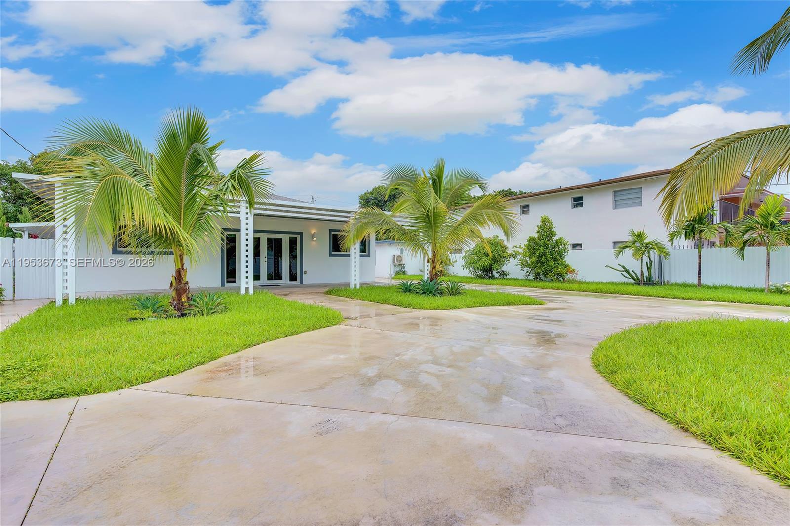 A single-story white house with a concrete driveway and palm trees under a blue sky — 2247 NW 2nd St, Miami FL 33125, MIAMI, FL