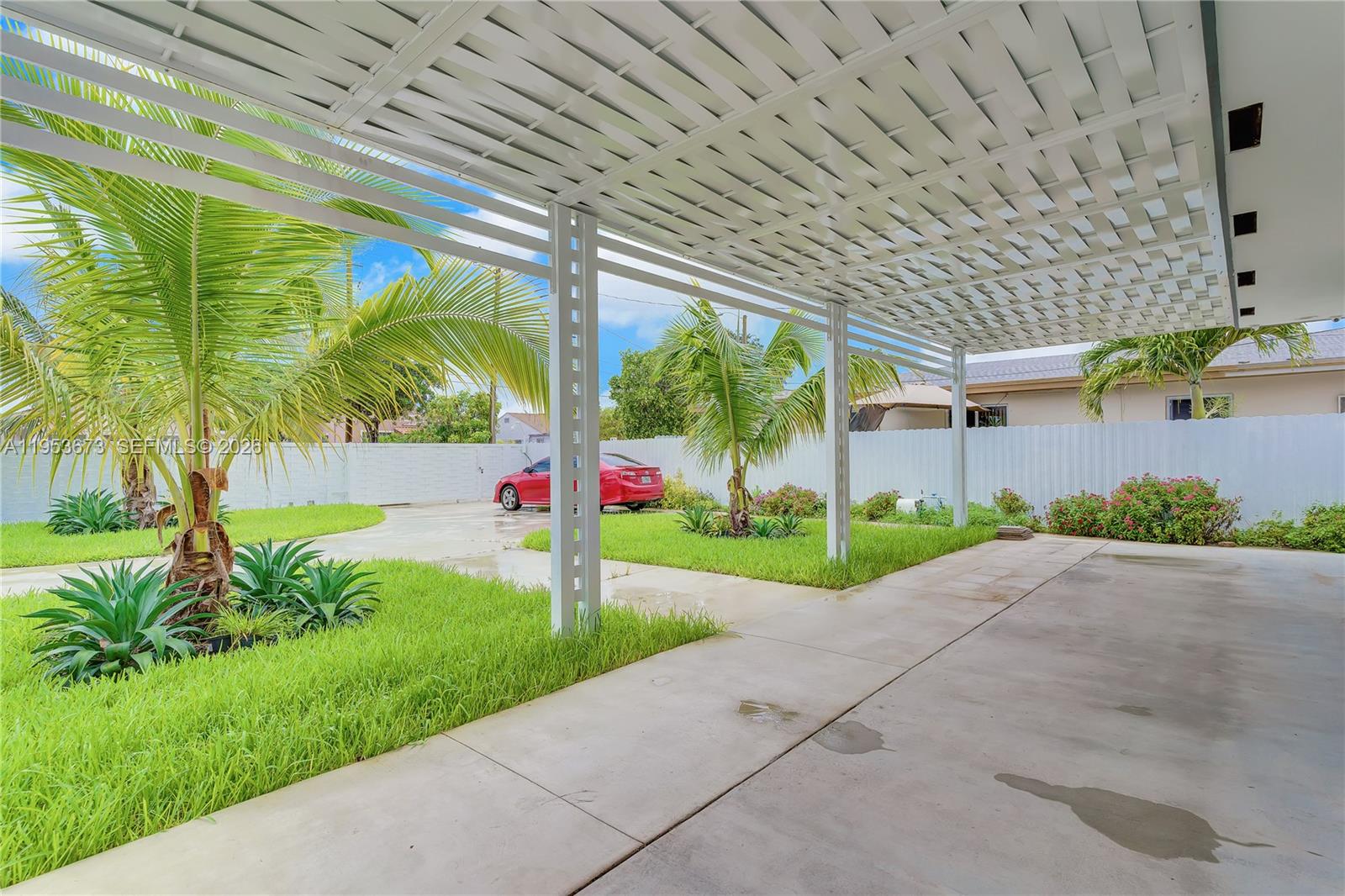 A covered patio with a white lattice roof overlooks a grassy yard and a red car — 2247 NW 2nd St, Miami FL 33125, MIAMI, FL