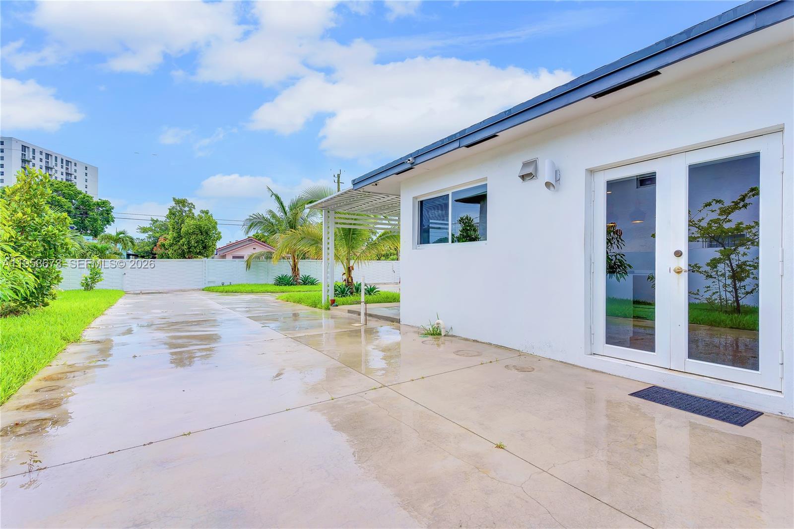 A white exterior wall features a window and glass double doors opening onto a patio — 2247 NW 2nd St, Miami FL 33125, MIAMI, FL