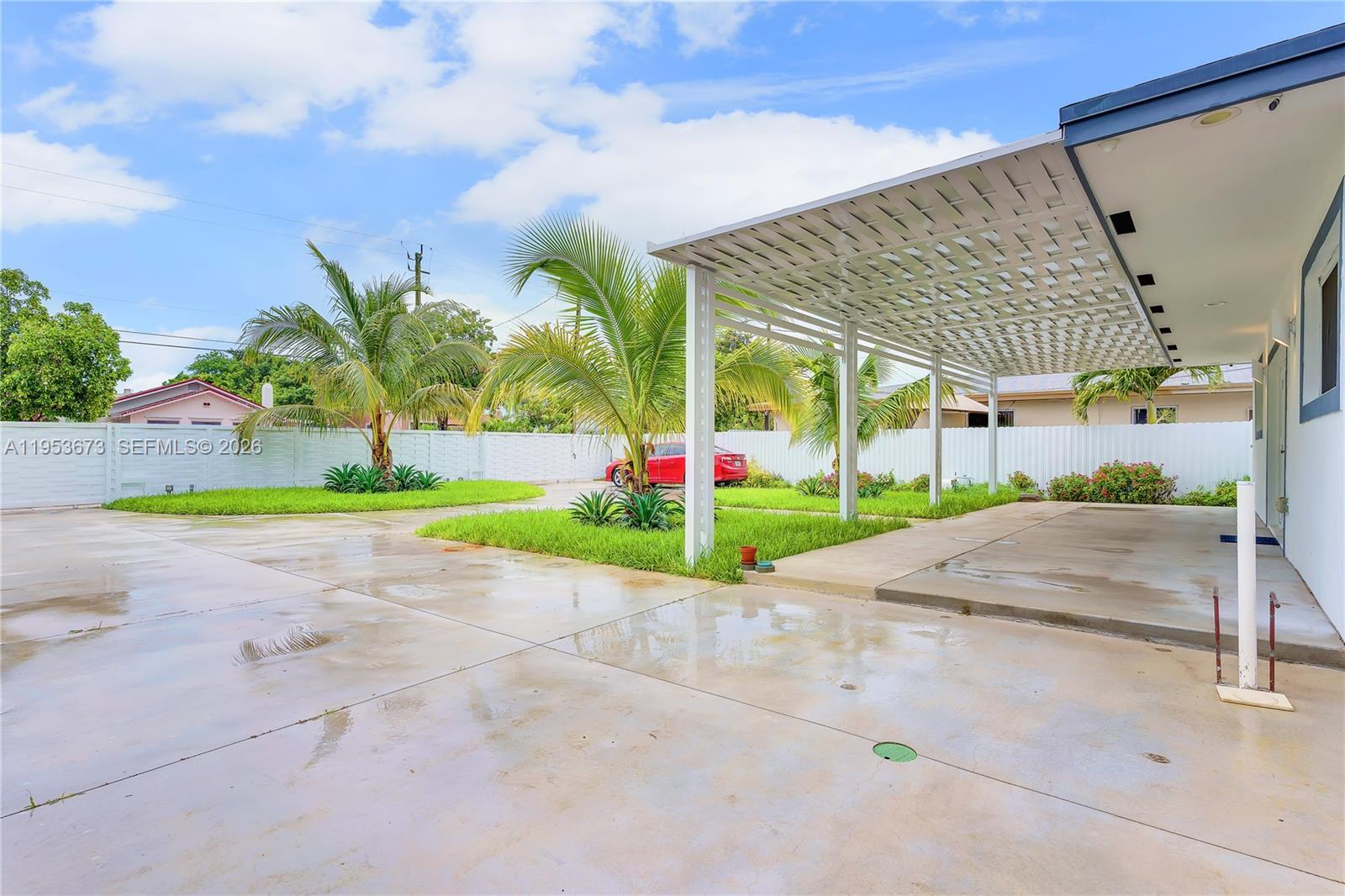 A concrete driveway leads to a white pergola attached to the side of a house — 2247 NW 2nd St, Miami FL 33125, MIAMI, FL