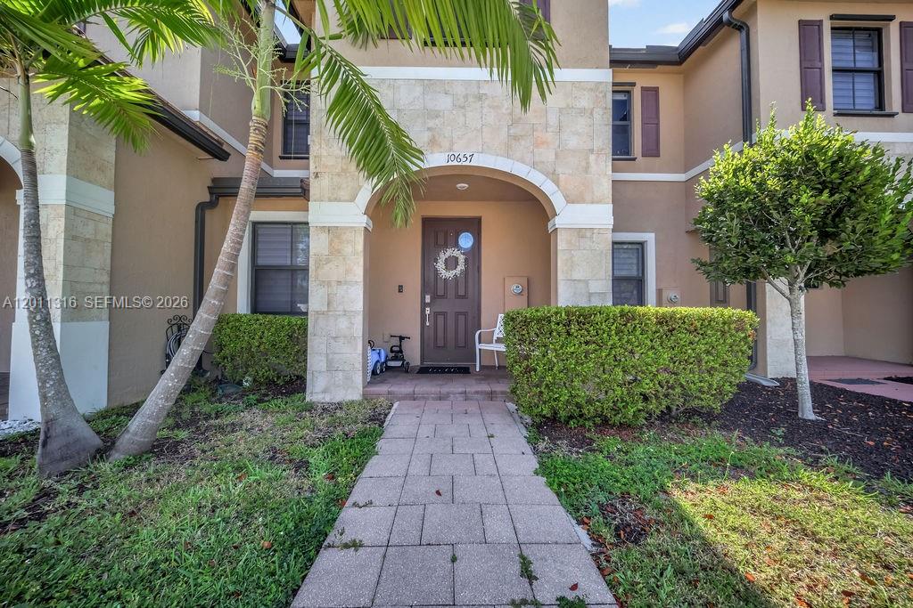 A stone-accented entryway features a brown front door, a paved walkway, and manicured landscaping — 10657 W 32nd Ln, Miami Lakes FL 33018, MIAMI LAKES, FL