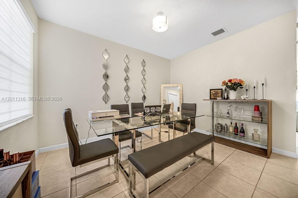 A dining room features a glass table, a bench, chairs, and a metal shelving unit — 10657 W 32nd Ln, Miami Lakes FL 33018, MIAMI LAKES, FL