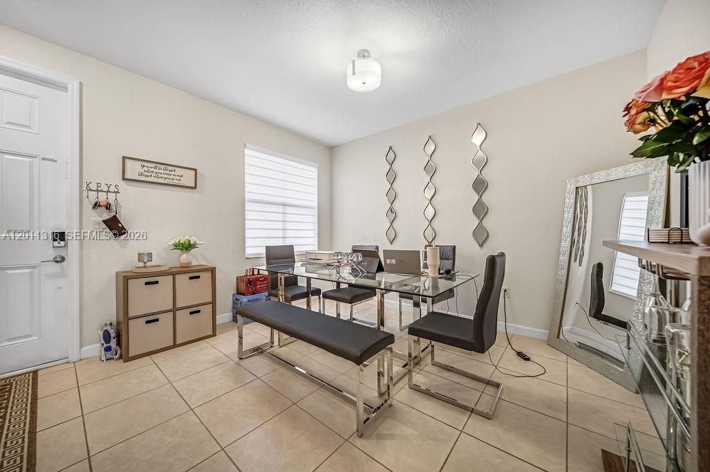 A dining room features a glass table, a bench, chairs, and a large floor mirror — 10657 W 32nd Ln, Miami Lakes FL 33018, MIAMI LAKES, FL