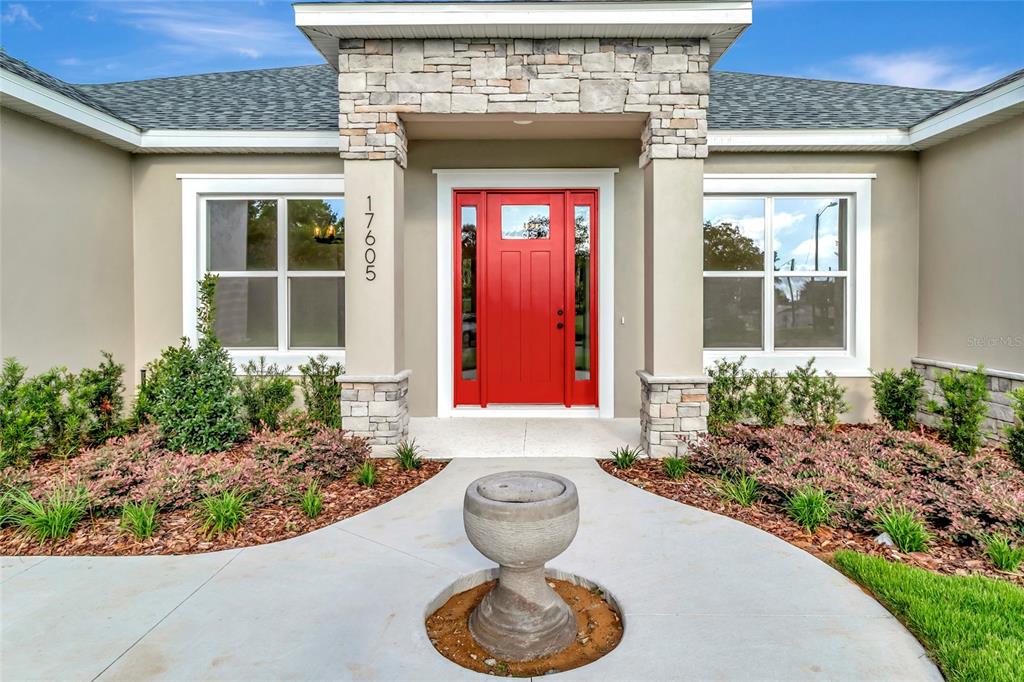 The exterior of a house features a bright red front door and stone-accented columns — 17605 NINTH STREET, MONTVERDE, FL