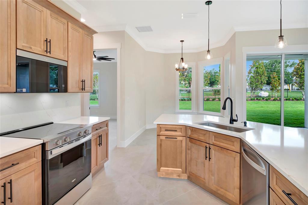 A kitchen with light wood cabinets, white countertops, stainless steel appliances, and a backyard view — 17605 NINTH STREET, MONTVERDE, FL