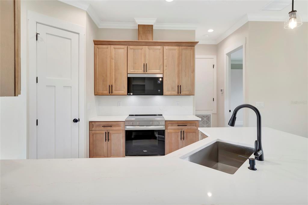 A kitchen features light wood cabinets, white countertops, stainless steel appliances, and a central island — 17605 NINTH STREET, MONTVERDE, FL