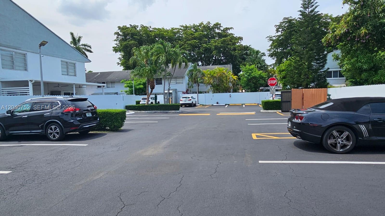A parking lot with two parked cars and a stop sign in front of buildings — 8460 SW 156th Pl # 702, Miami FL 33193, MIAMI, FL
