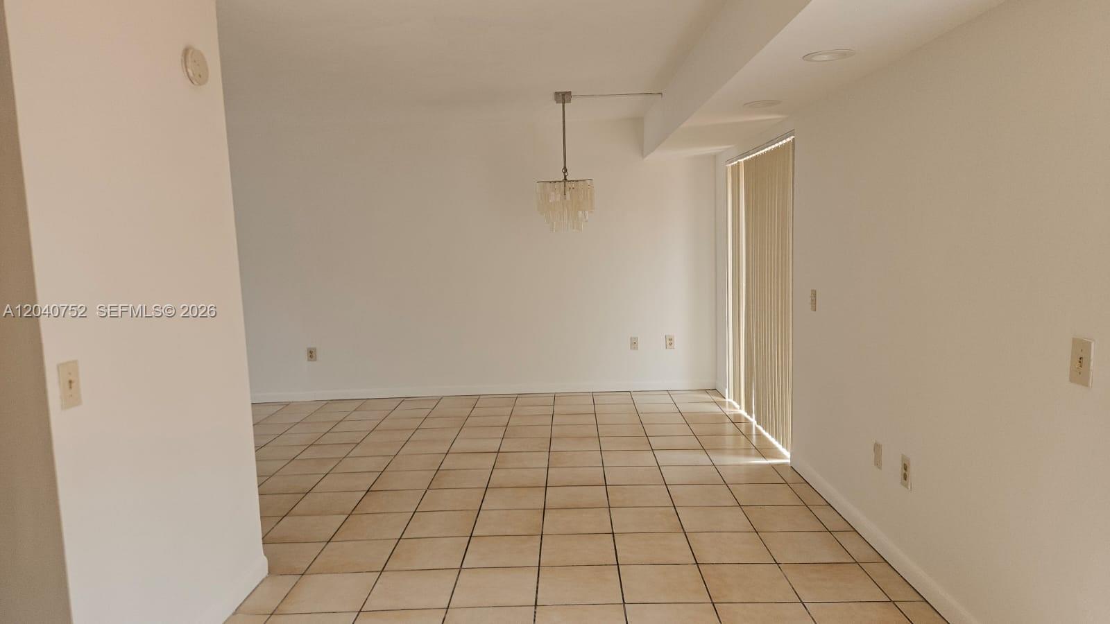 An empty room with white walls, tile flooring, and a hanging chandelier — 8460 SW 156th Pl # 702, Miami FL 33193, MIAMI, FL