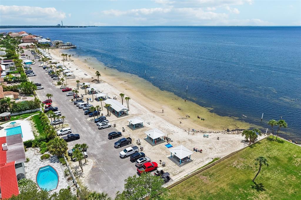 An aerial view shows a beach with parking, picnic pavilions, and a swimming pool — 5727 BISCAYNE COURT UNIT 209, NEW PORT RICHEY, FL