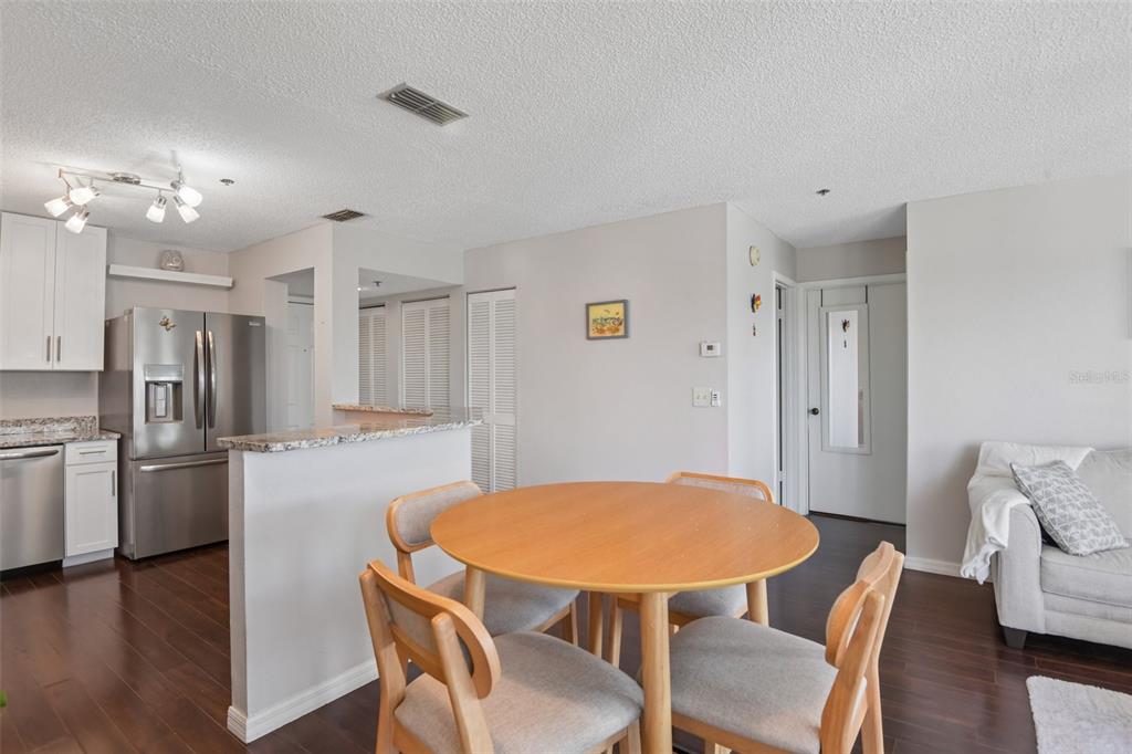 A dining area with a round wooden table and chairs adjacent to a modern kitchen — 5727 BISCAYNE COURT UNIT 209, NEW PORT RICHEY, FL