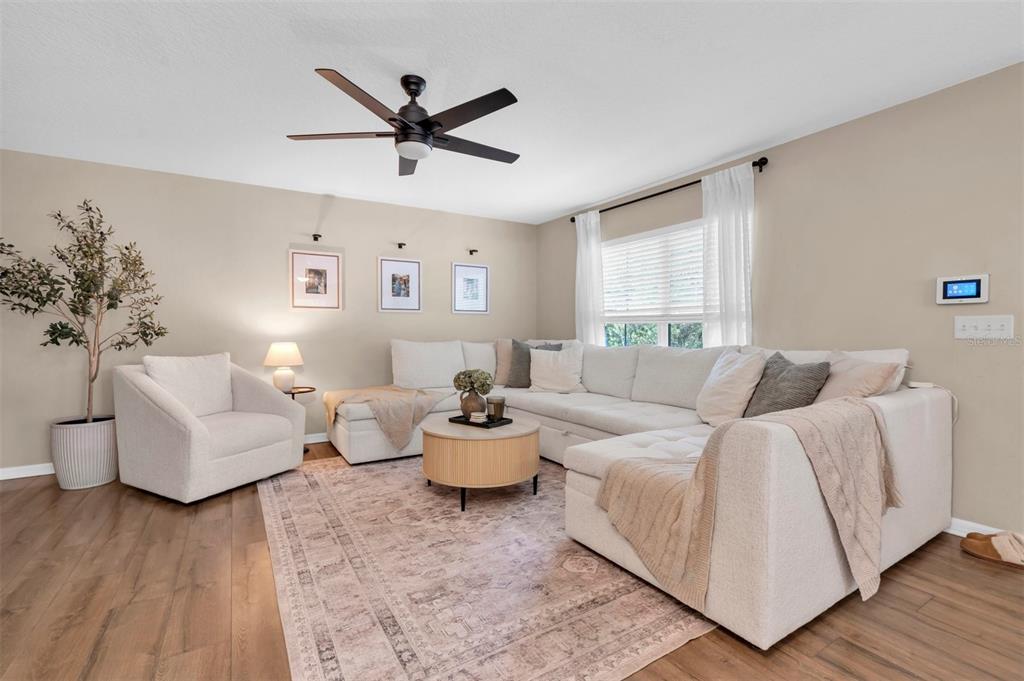A living room features a white sectional sofa, an armchair, and a round coffee table — 9548 CHARLESBERG DRIVE, TAMPA, FL